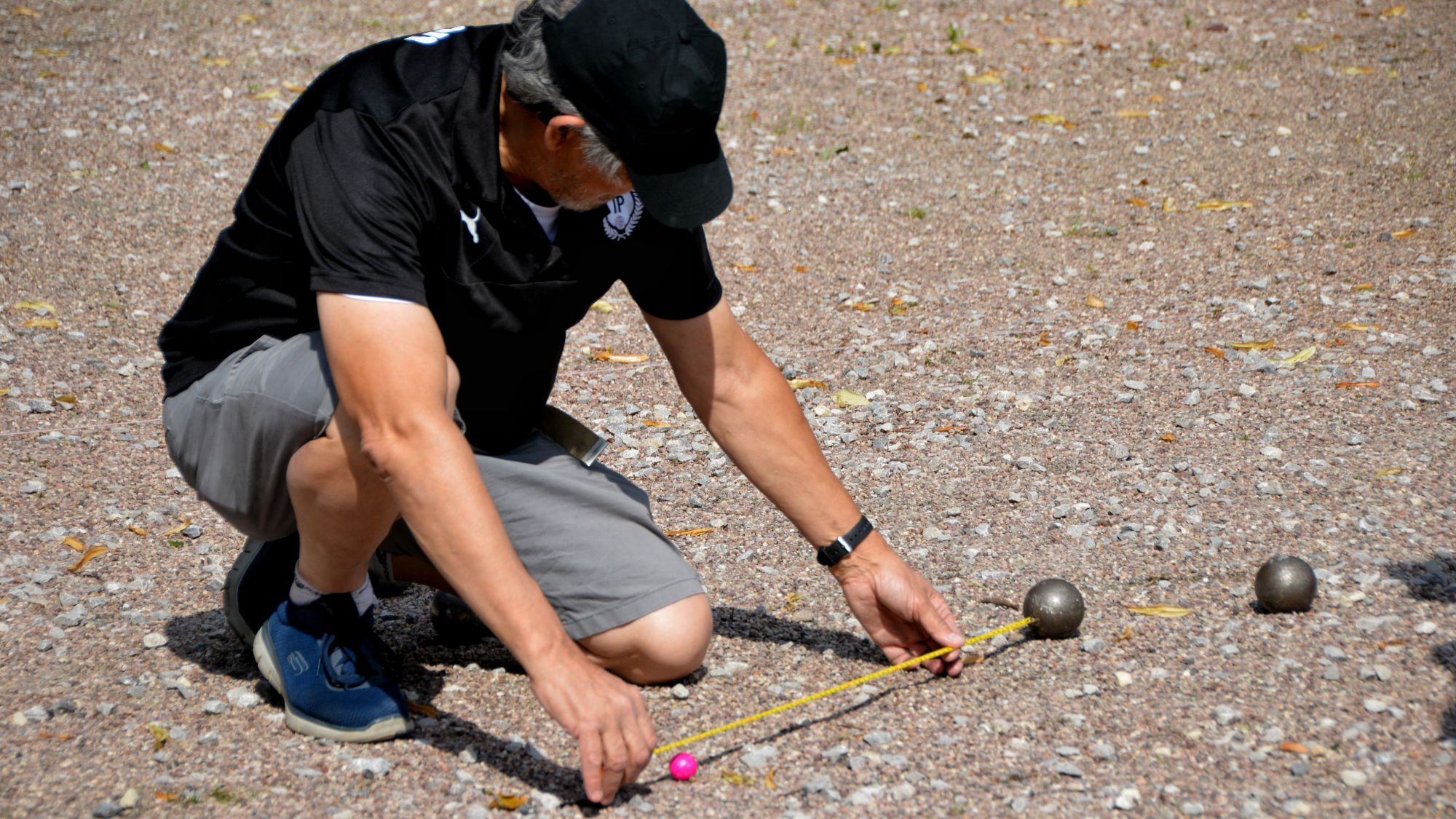 Pétanque player measuring for the point